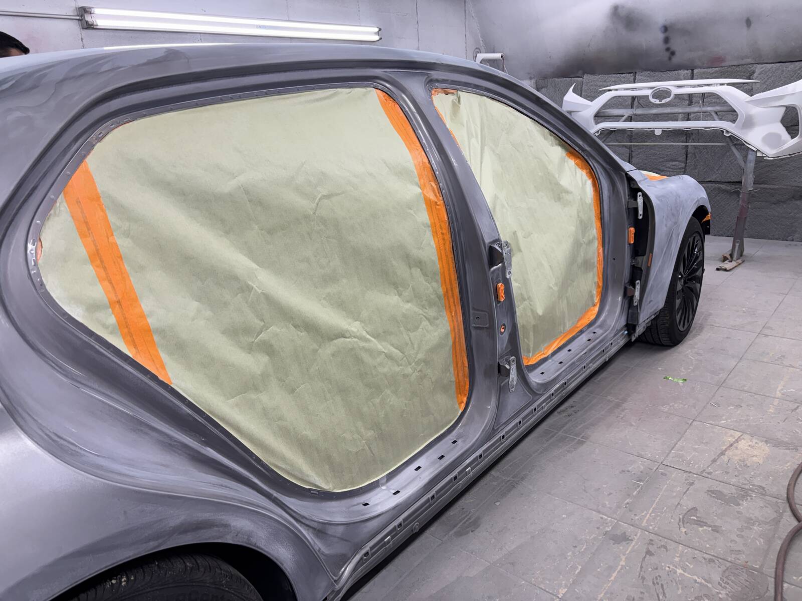 A car in gray primer with the windows masked off, ready for new paint.